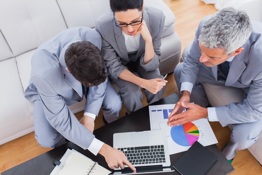Serious business people using laptop and working together on sofa at office Serious business people using laptop and working together on sofa at office